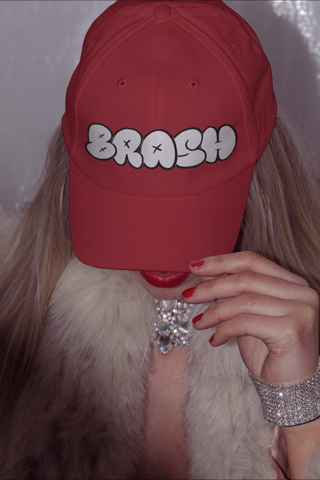 Woman wearing a red cap with bold font design, paired with fur and jewelry, suitable for fashion mockups and accessory templates.